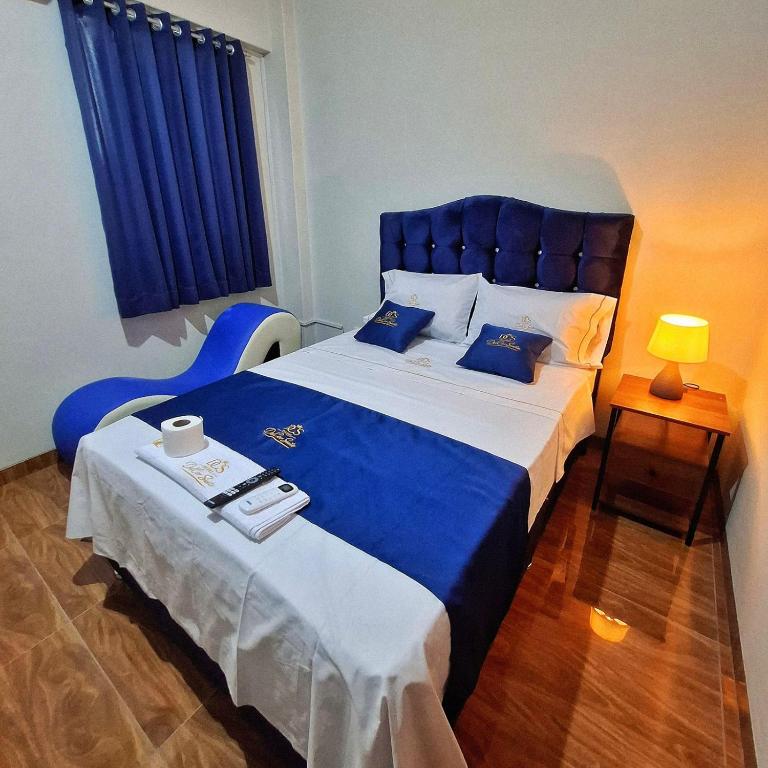 a bedroom with a large bed with a blue headboard at Hotel Delcor Suite in Piura