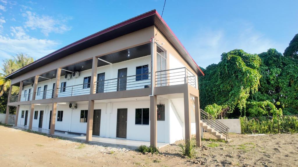 a large white building with trees in the background at F&D Homestay in Semporna