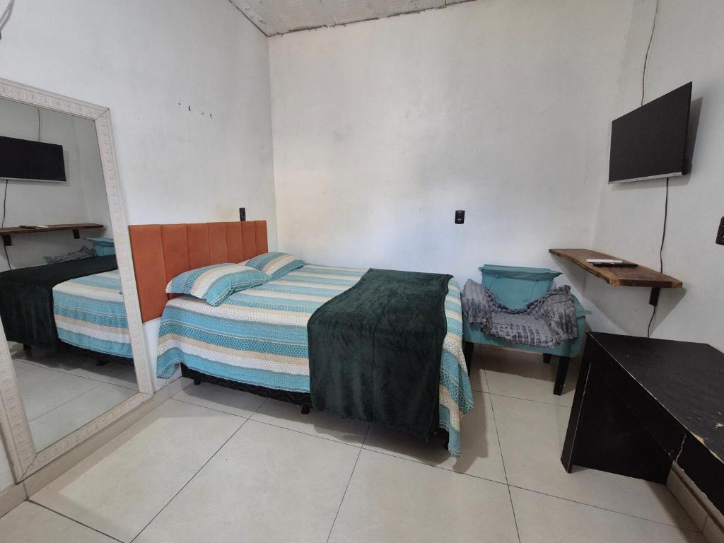 a small bedroom with a bed and a mirror at Hospedaria Caripí - Suíte 03 in Barcarena