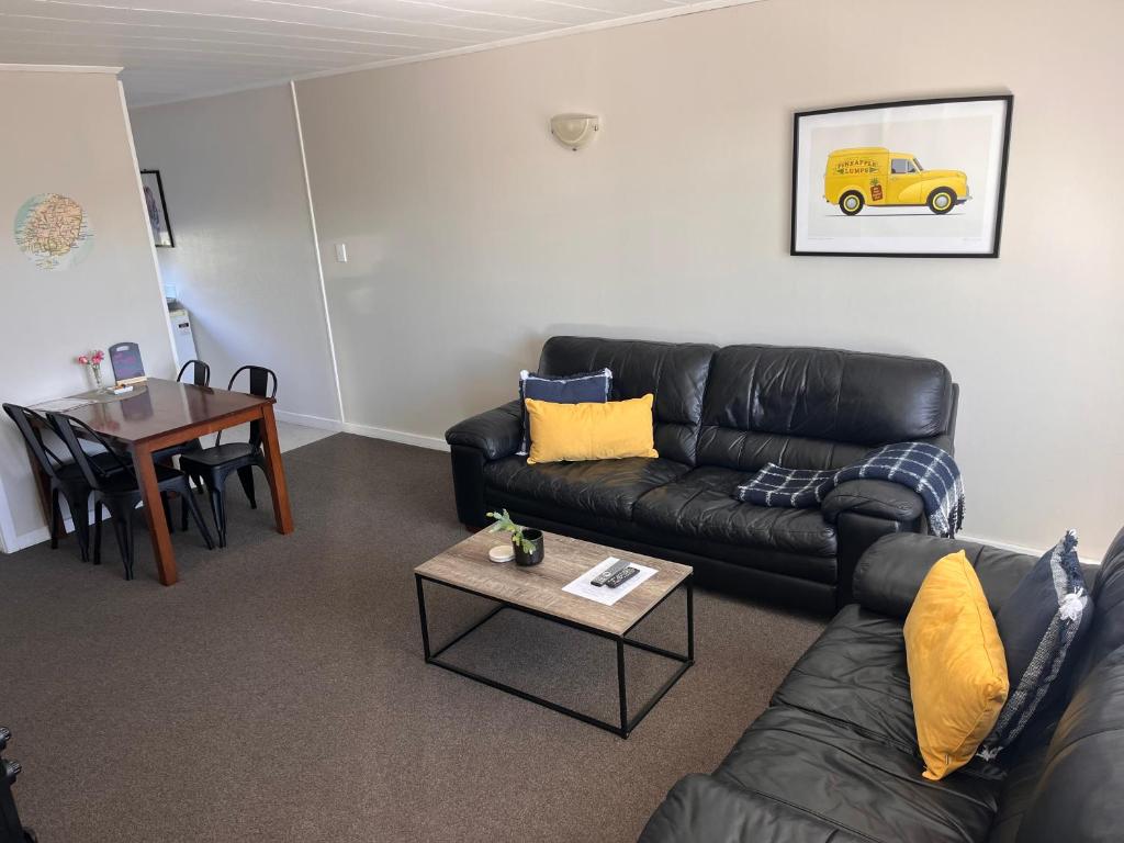a living room with a black leather couch and a table at Aorangi Motel in Fairlie