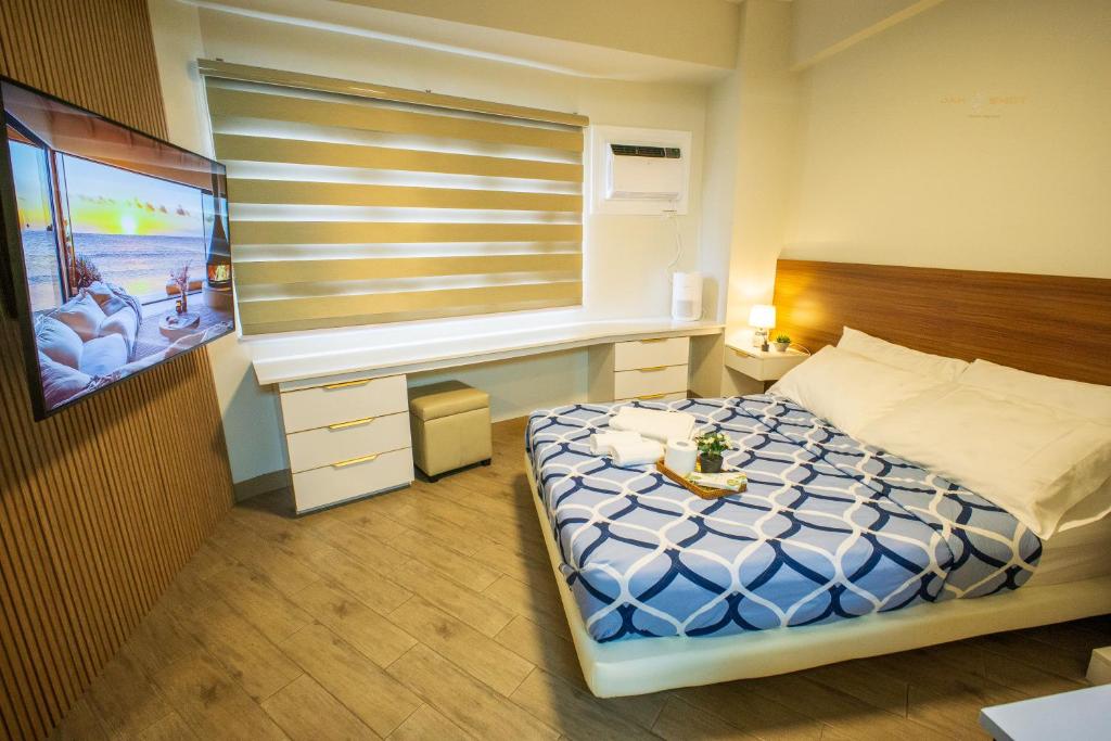 a bedroom with a bed with a desk and a window at Voice activated studio condo unit at One Regis Megaworld, JK Modern Nest in Bacolod