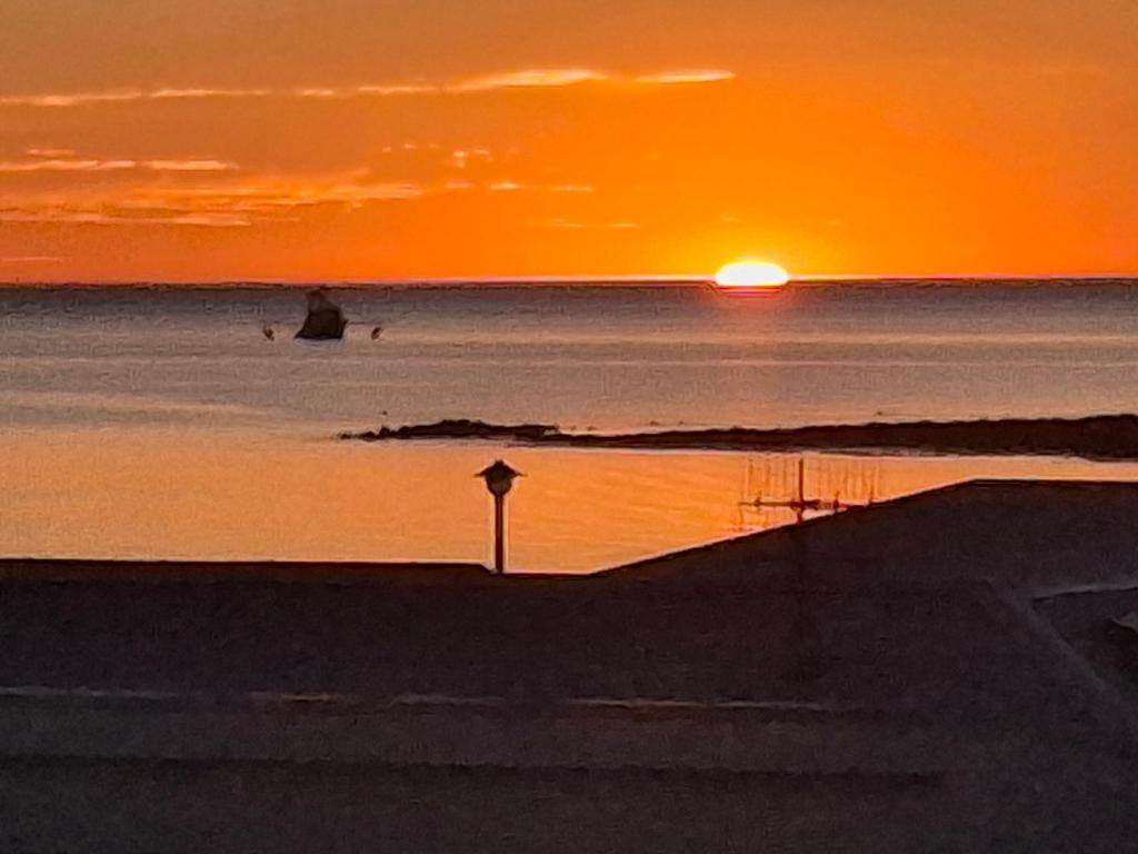 a sunset on the beach with the sun setting at Sunsethome Wallaroo in Wallaroo