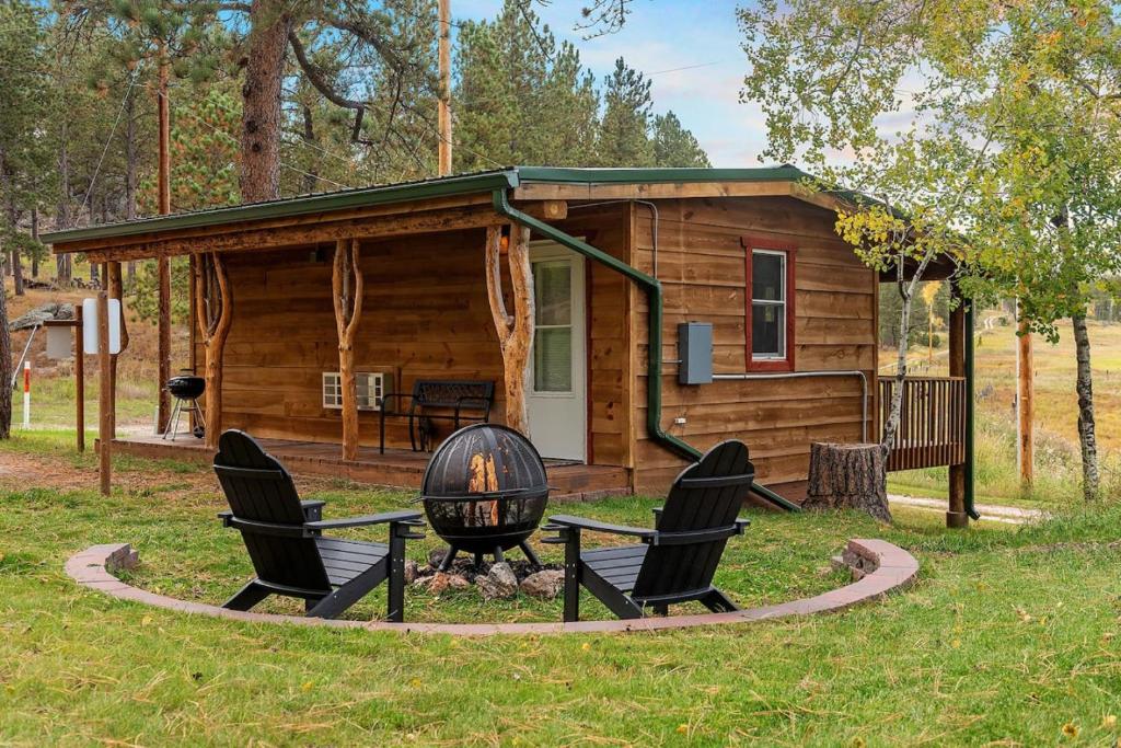 a log cabin with chairs and a grill in front of it at Mountain View Gem BHBungalows #2 in Custer
