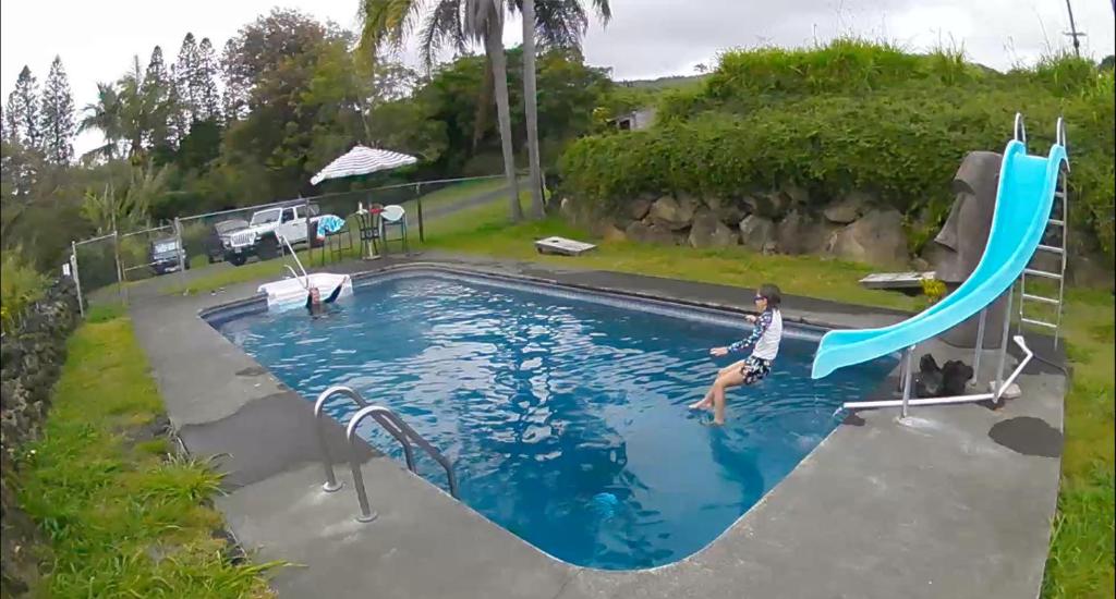 a man jumping off a slide in a swimming pool at Hawaii Island Resort in Naalehu