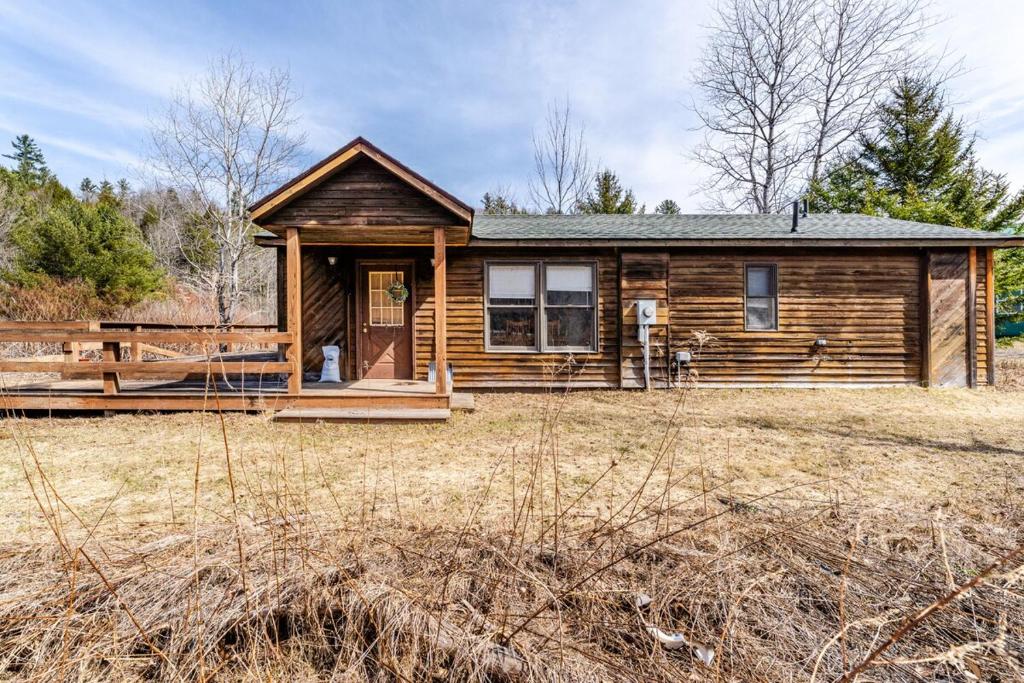 a log cabin with a porch in a field at Ski Bowl Cottage! in Hunter