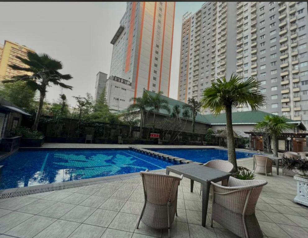 a swimming pool with a table and chairs and buildings at Apartemen Ciumbuleuit 2 in Bandung