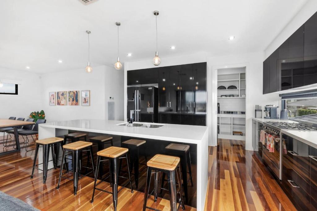 a kitchen with a white counter and bar stools at Bayview Luxe- Sleeping 14, Pet Friendly, Views- 4 bedroom, lounge with sofa beds in Curlewis