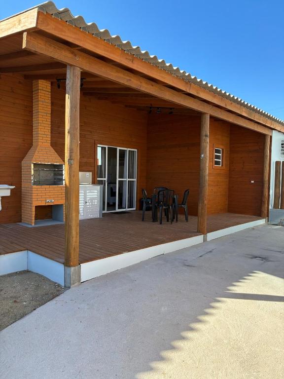 a covered deck with a table and chairs on it at Casa Dunas - Las Caracolas - Cassino RS in Rio Grande