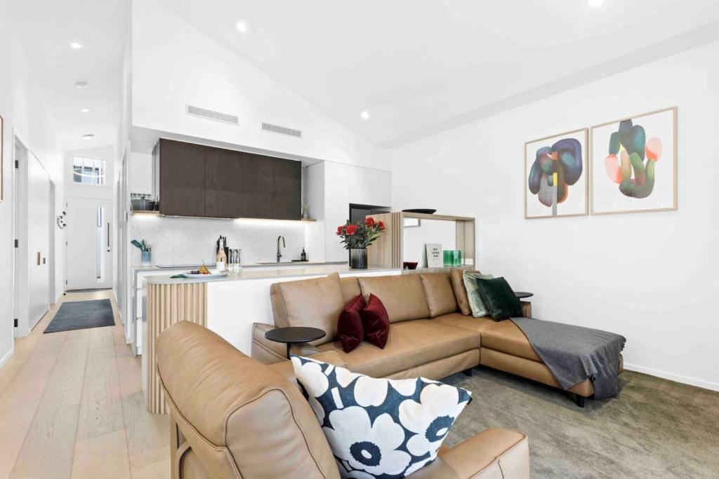 a living room with a couch and a kitchen at Mod House Ocean Grove- Walk to the shops, cafes, beach and park! Brand new luxury apartment in gated complex in Ocean Grove