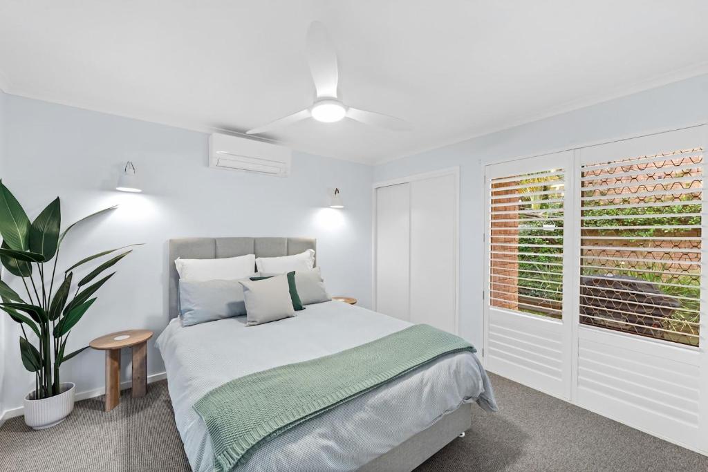 a white bedroom with a bed and a window at Beach Street - Town Location - Stone Real Estate Yamba in Yamba