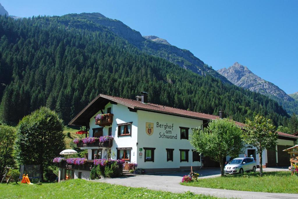 a building with flowers in front of a mountain at Berghof am Schwand in Hinterhornbach