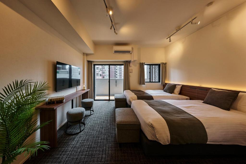 a hotel room with three beds and a flat screen tv at Grand Residence Hotel Hakata Premier in Fukuoka