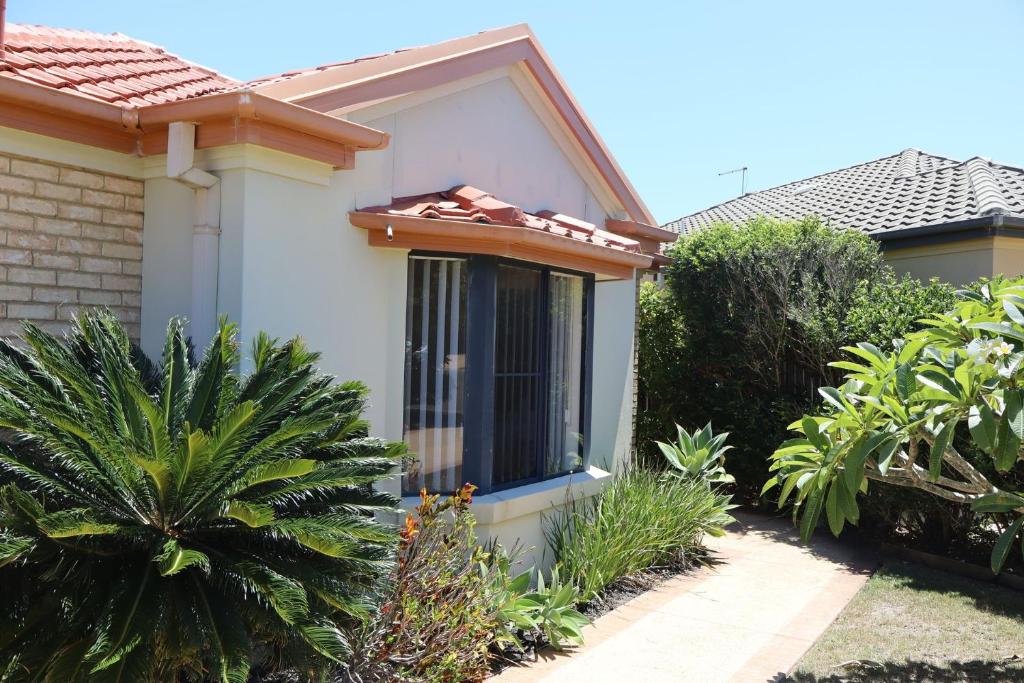 a white house with a window in a garden at Oceania Cottage- Pet Friendly -Stone Real Estate Yamba in Yamba
