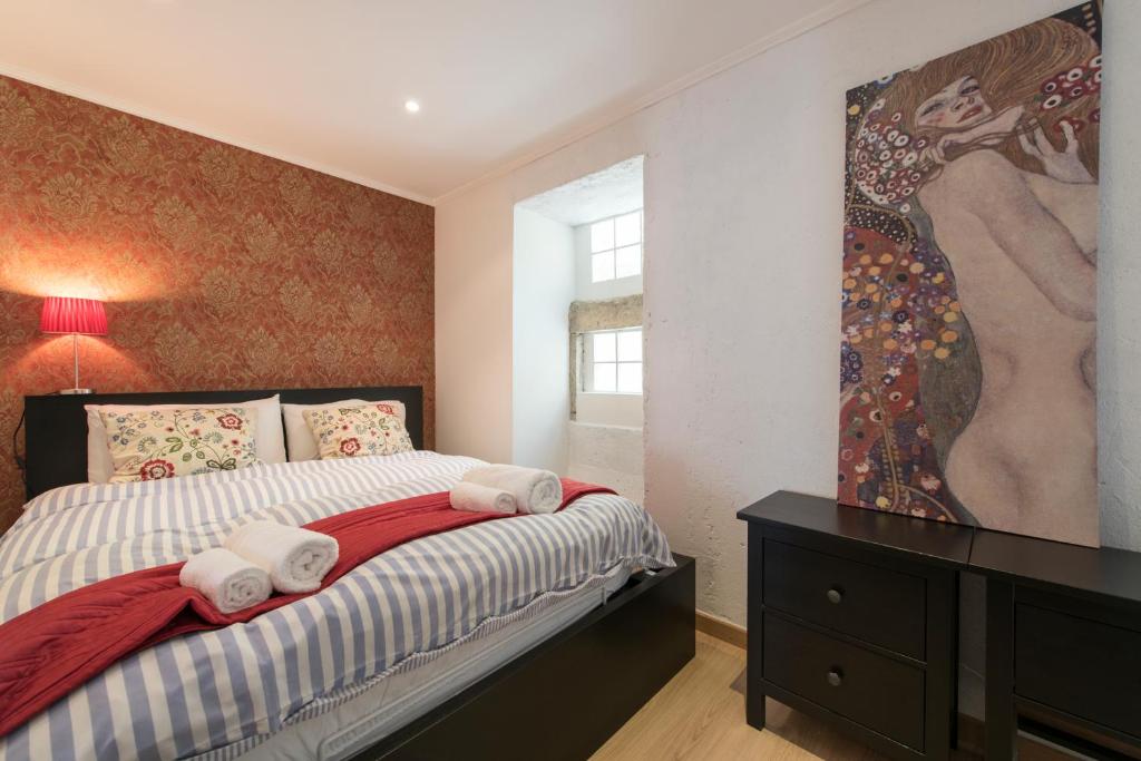 1 dormitorio con 1 cama y una pintura en la pared en Lusitania One in Mouraria, en Lisboa