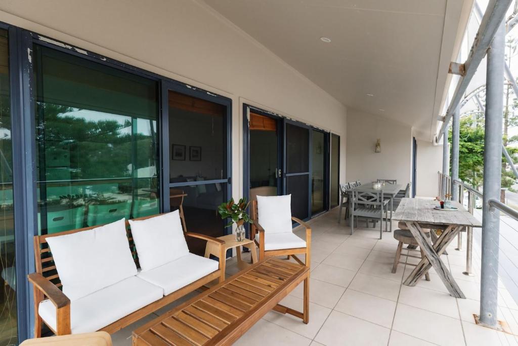 a living room with a couch and chairs on a balcony at Six River - Town Location - Stone Real Estate Yamba in Yamba