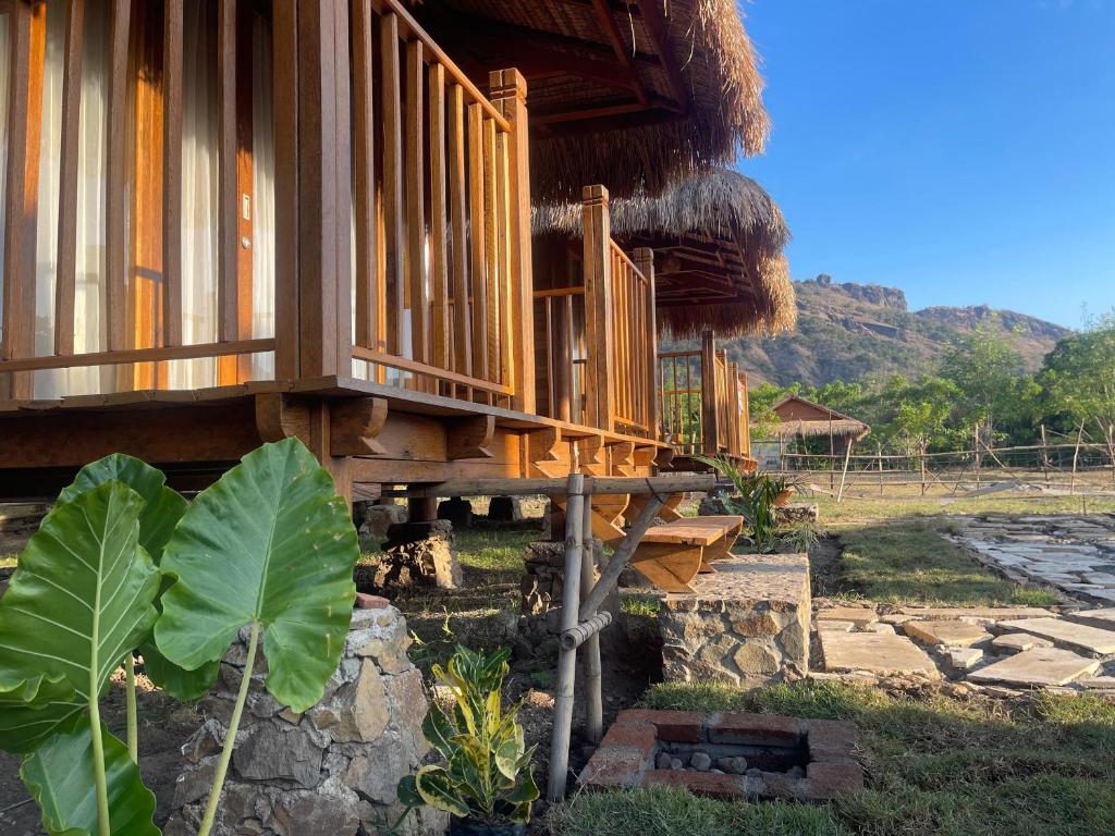 a wooden building with a porch and a grass roof at Morgans Bungalows in Maluk