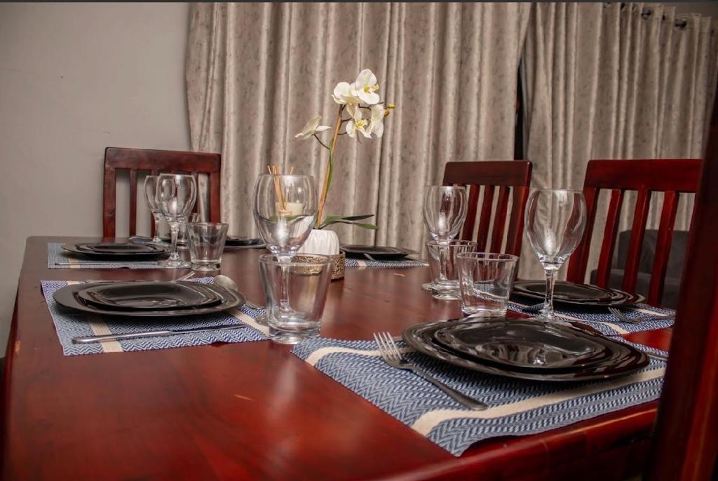 a table with glasses and plates and a vase with a flower at MbaliBliss in Bulawayo