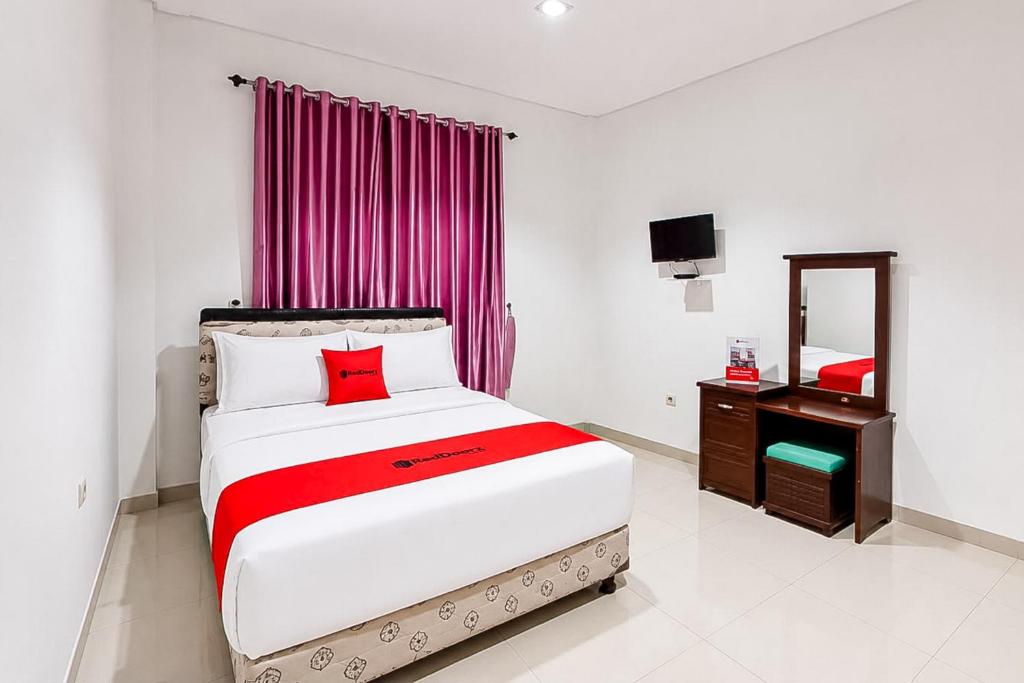 a bedroom with a large bed and a mirror at RedDoorz at Residence Bintaro in Mencil