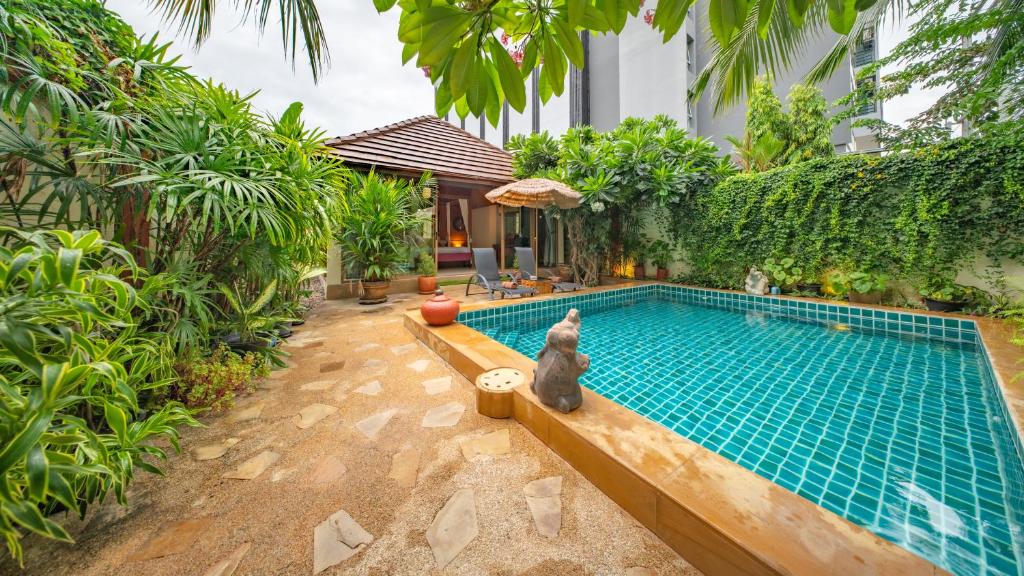 a dog sitting next to a swimming pool at Pattaya Bungalow II, Totally Private Pool in Pattaya South