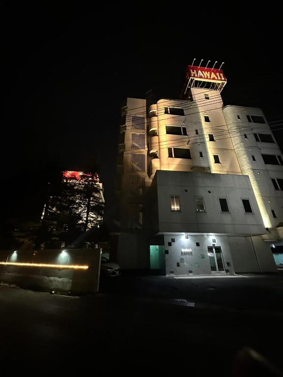 ein Gebäude mit einem Neonschild auf dem Dach in der Nacht in der Unterkunft ロコズリゾートハワイandオアフ in Honjo