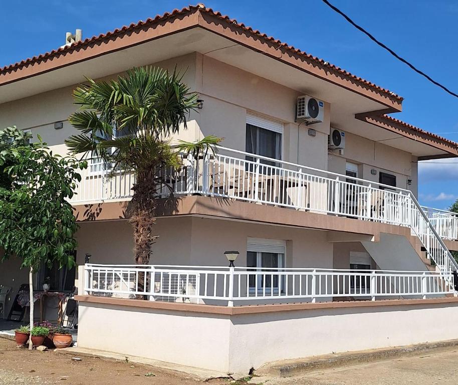 a white house with a balcony and a palm tree at Imeros Summer Home in Ímeros