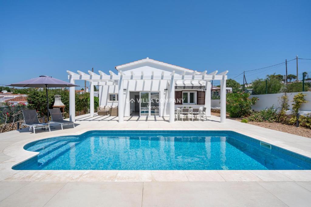 a swimming pool in front of a house at Villa de Amigos in Cala en Porter