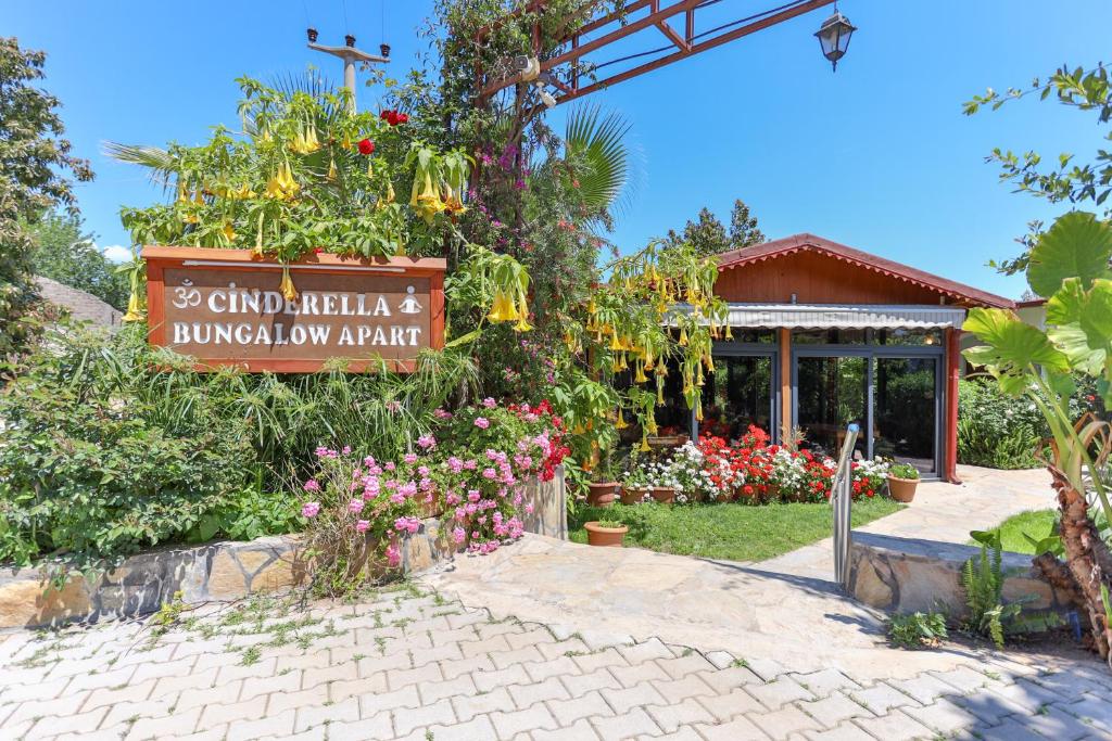 a sign in front of a garden with flowers at Cinderella Pension & Bungalow in Cıralı