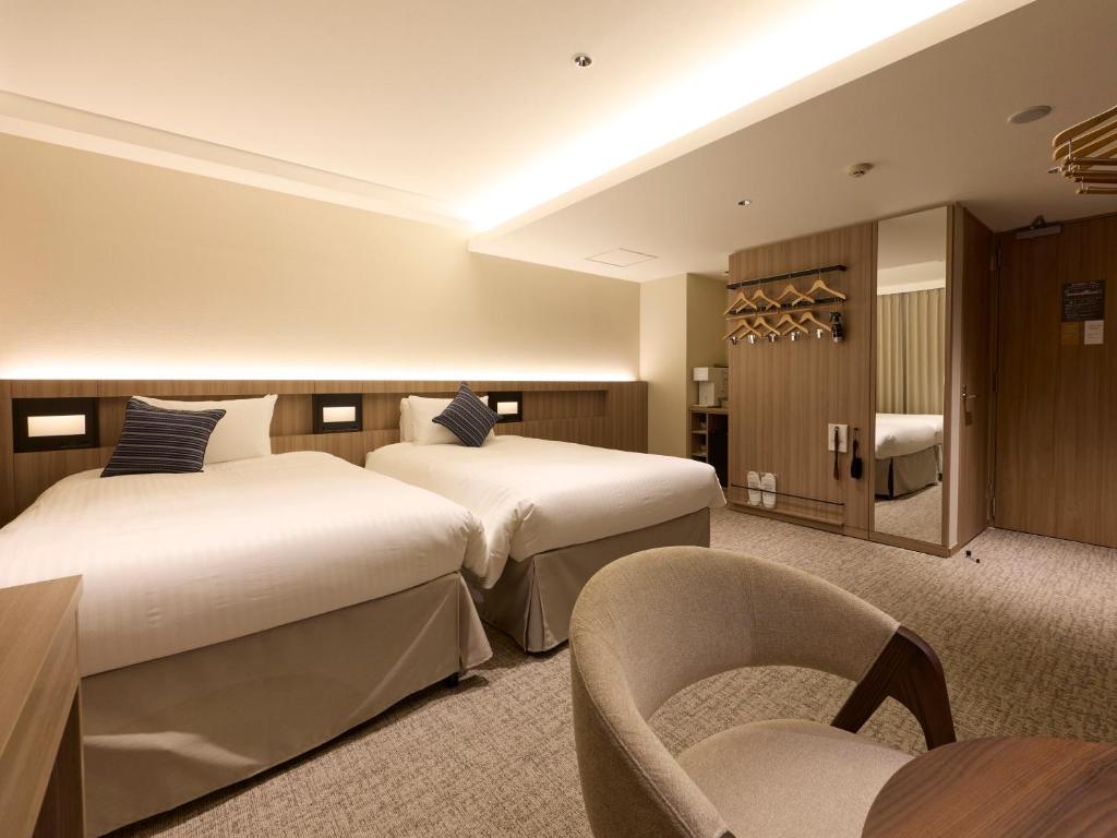 a hotel room with two beds and a chair at Shizutetsu Hotel Prezio Hakataekimae in Fukuoka