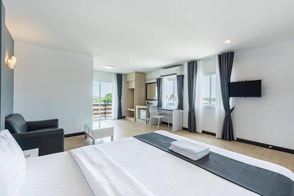 a bedroom with a white bed and a living room at Le Nara Residence in Jomtien Beach