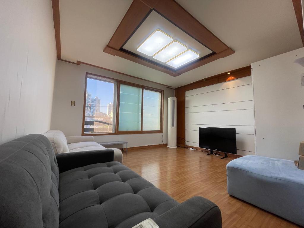 a living room with a couch and a flat screen tv at BV House in Incheon