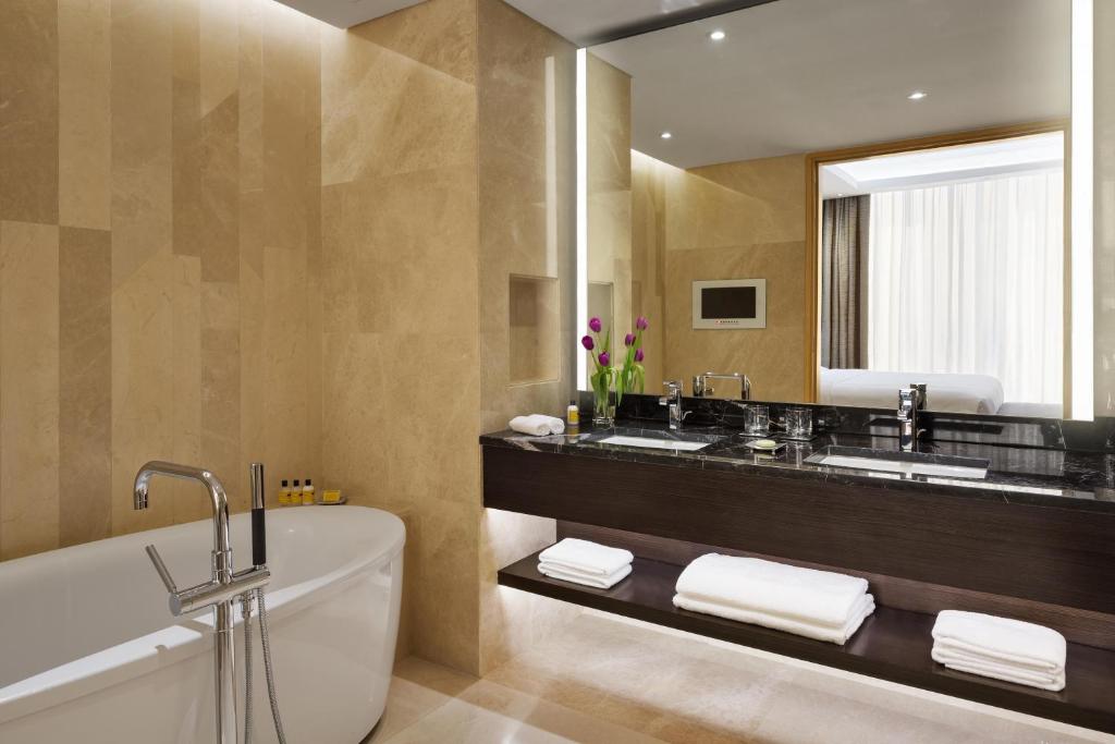 a bathroom with a tub and a large mirror at Hyatt Regency Riyadh Olaya in Riyadh