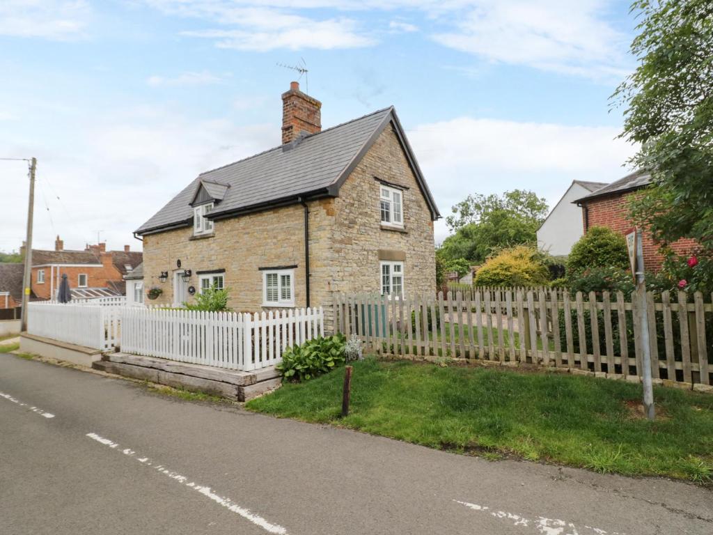 a brick house with a white picket fence at The Cottage in Stratford-upon-Avon