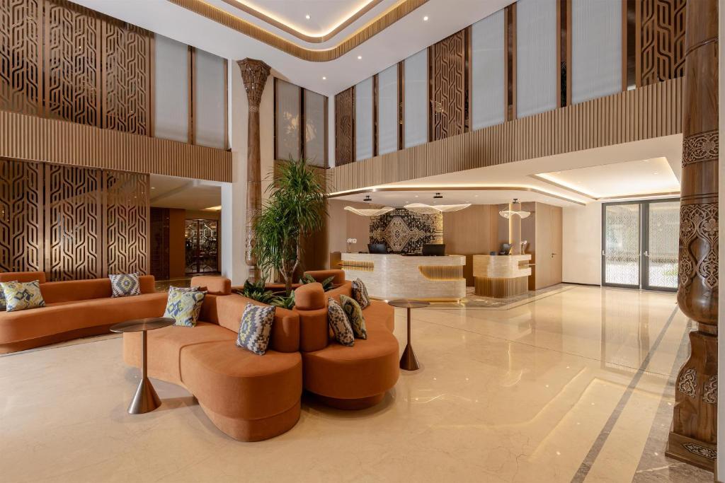 a lobby with orange furniture and a living room at Doubletree By Hilton Tashkent in Tashkent