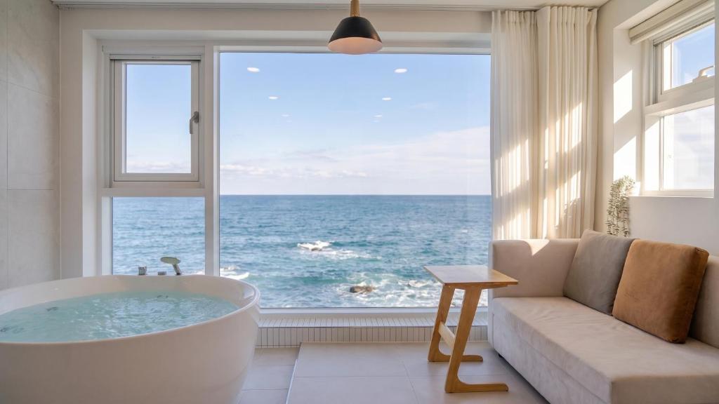 a bathroom with a tub and a large window with the ocean at Donghae Badadam Ocean View Spa Pension in Donghae