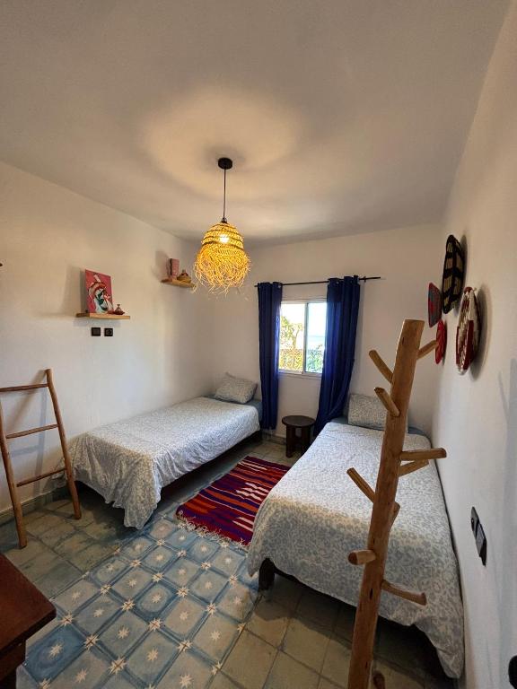 a bedroom with two beds and a chandelier at Jara Cimrmann surf house in Imsouane