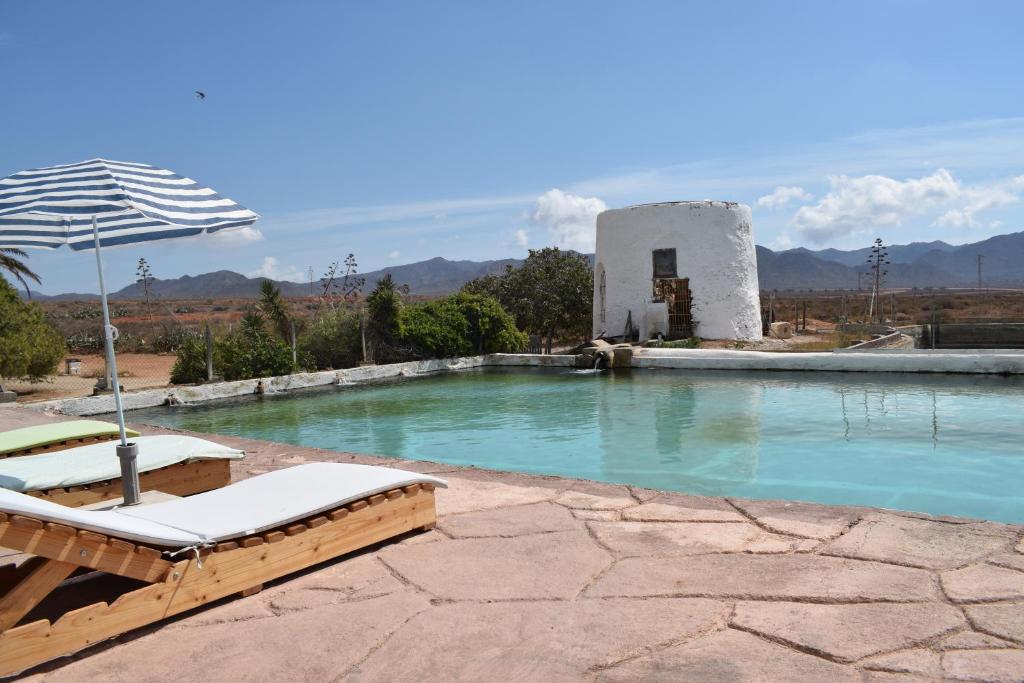 een zwembad met 2 ligstoelen en een parasol bij Cortijo La Molina de Cabo de Gata in El Cabo de Gata