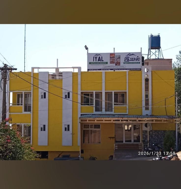 a yellow and white building with a sign on top at Iyal Hotels and Resorts in Salem