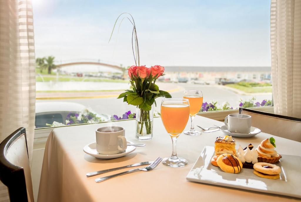 uma mesa com um prato de comida e um vaso de flores em Hotel Presidente em Mar del Plata