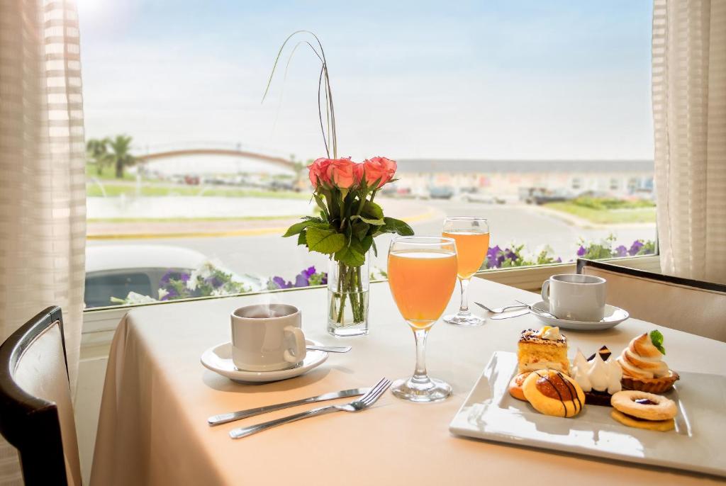 una mesa con un plato de comida y un jarrón de flores en Hotel Presidente en Mar del Plata