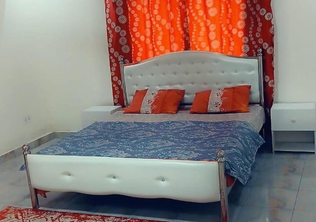 a bedroom with a bed with an orange curtain at Zahra Suites in Elephant Island