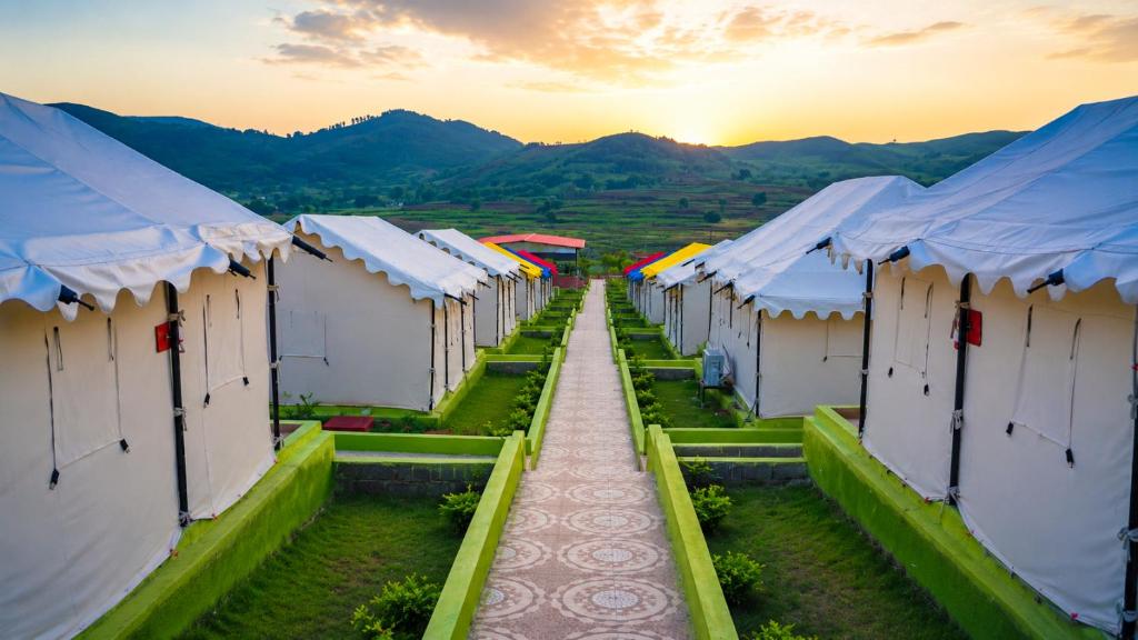 a row of houses with the sunset in the background at Sumitel Araku Mount View Camping Resort in Sunkarimetta