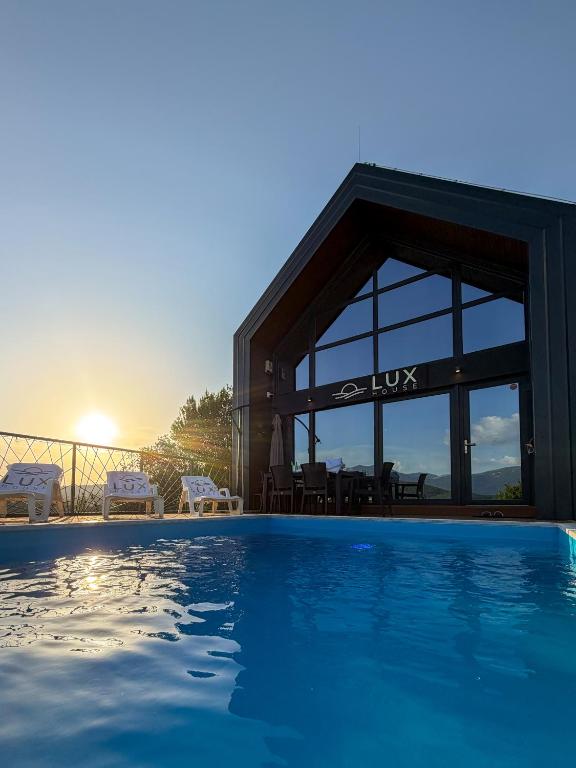 a house with a swimming pool in front of a building at Lux House in Hadžići