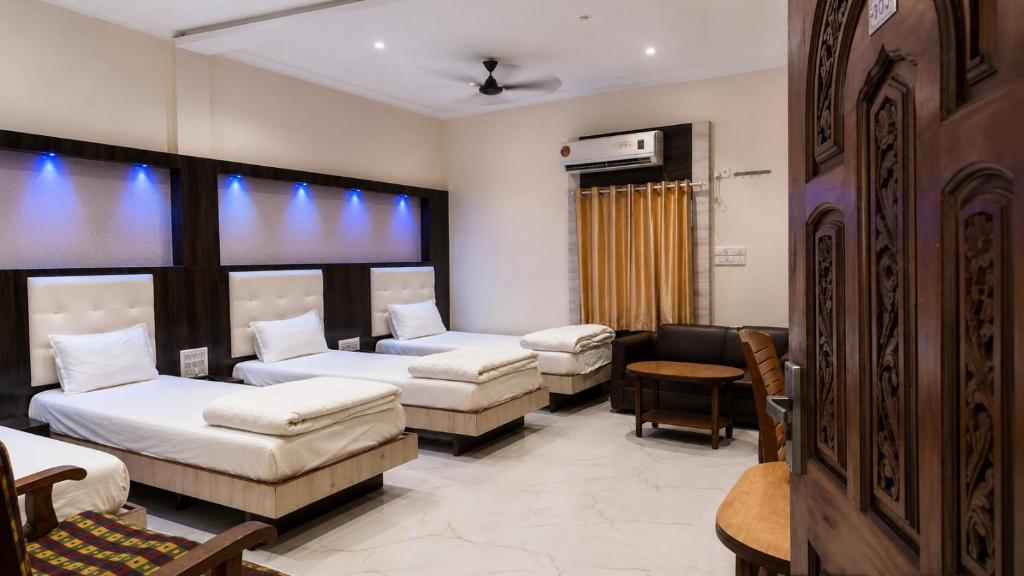 a room with three beds and a waiting room at Hotel Volga 2 in Mumbai