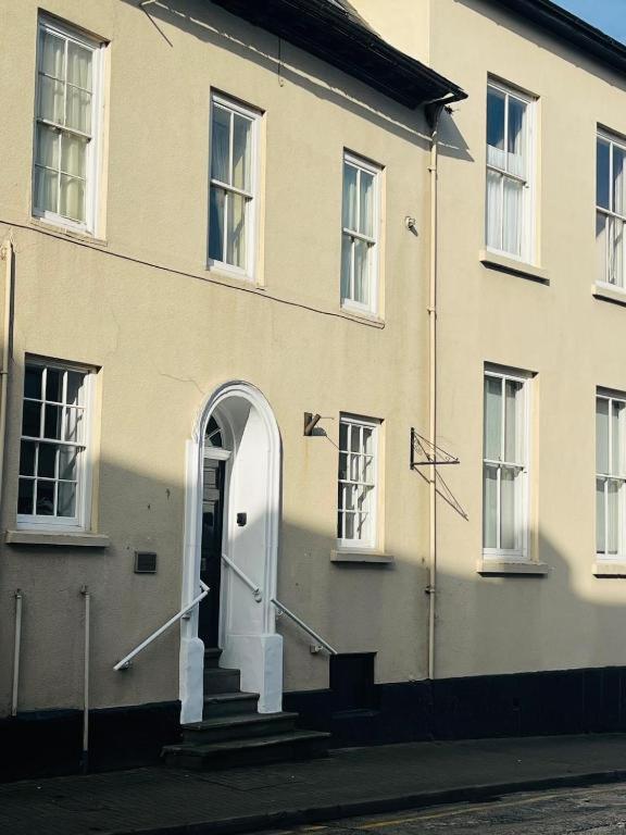 a white building with a white door and stairs at 2 Bed Period Flat with parking in Ross on Wye