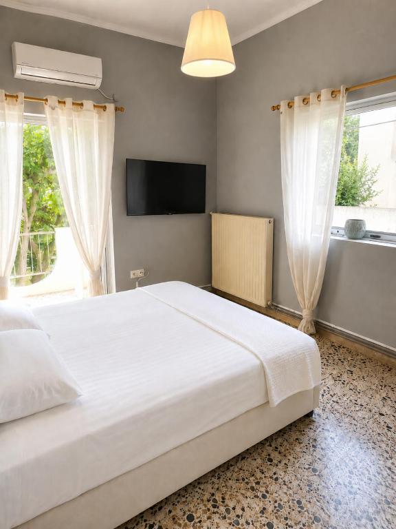 a bedroom with a large white bed and a television at Margianna Apartments1 in Káto Ássos