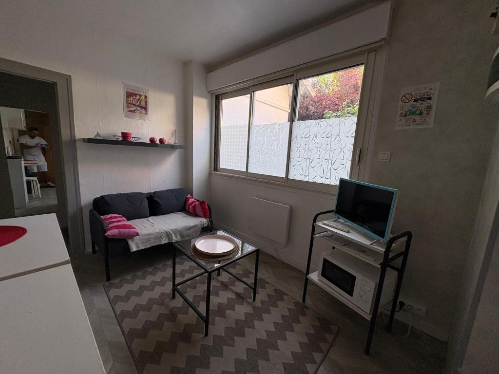 a small living room with a couch and a television at studio à deux pas du bassin in Arcachon