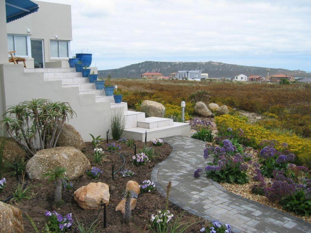a garden with stairs and flowers in front of a house at Dunestone Boutique GuestHouse in Langebaan