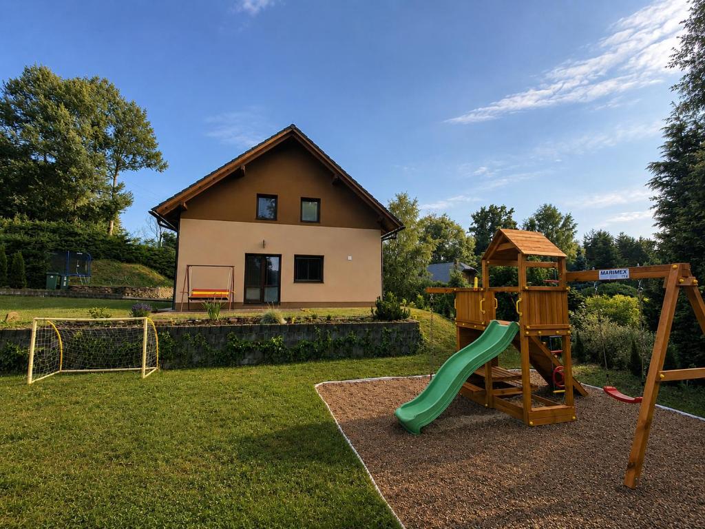 a playground with a slide in a yard with a house at Ubytování Dědinka in Mladkov