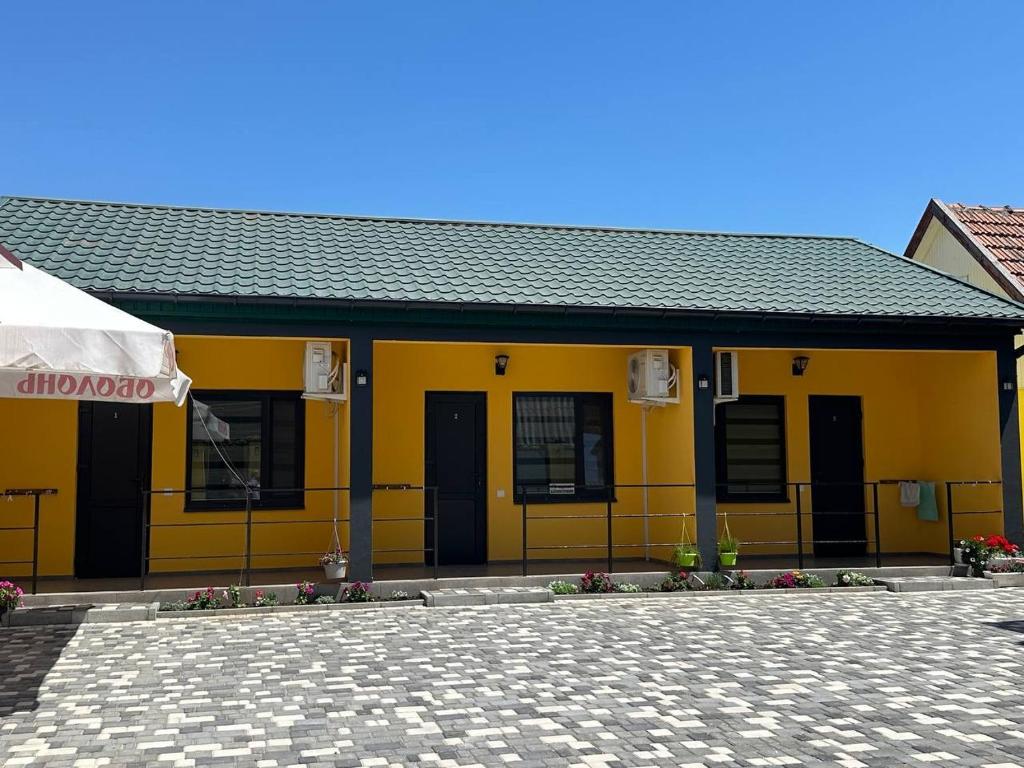 a yellow building with black doors and a roof at MANGO hotel in Zatoka
