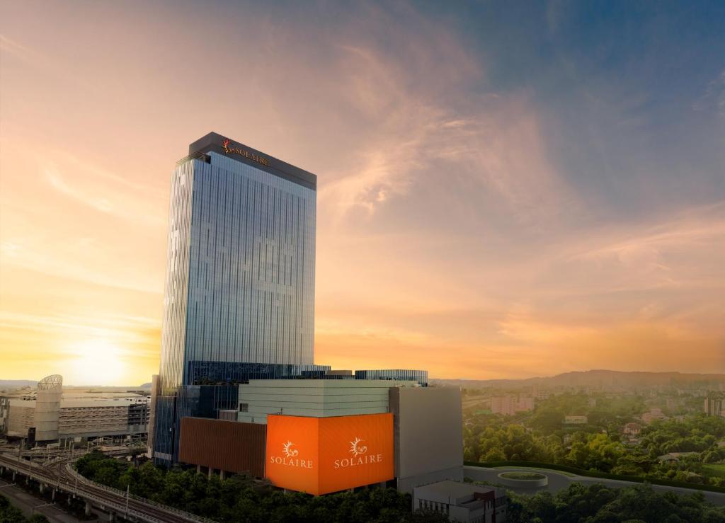 a tall office building with a sunset in the background at Solaire Resort Quezon City - Previously known as Solaire Resort North in Manila